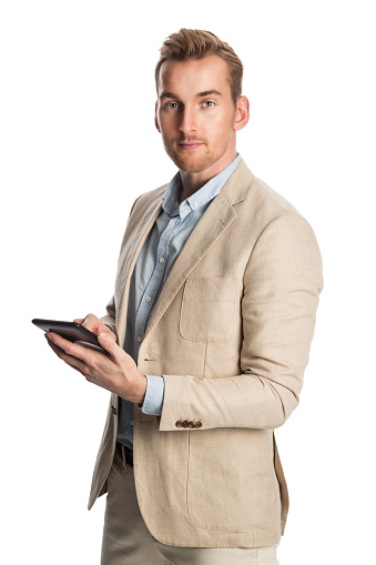 Mature man wearing a bright khaki blazer standing against a white background smiling holding a digital tablet.