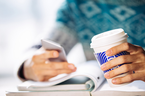 young asian man student with sweater holding mobile in library