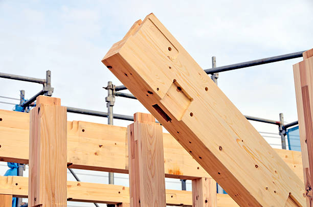 A symmetrical view of wooden roof trusses and beams in a finished attic space, showcasing precise carpentry and natural wood texture. The warm tones and clean lines emphasize structure, craftsmanship, and architectural design. The image reflects sustainable construction and interior detail.