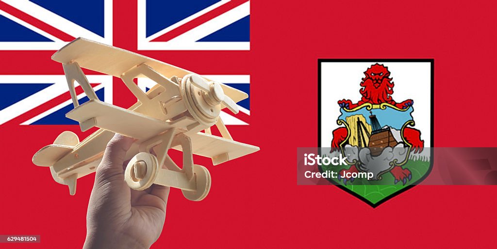 Hand holding airplane plane over Bermuda flag, travel concept Activity Stock Photo