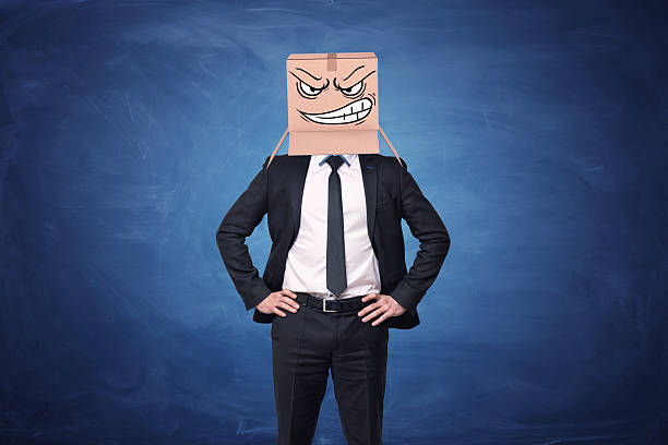 istock Businessman is wearing cardboard box with drawn angry face 629484358