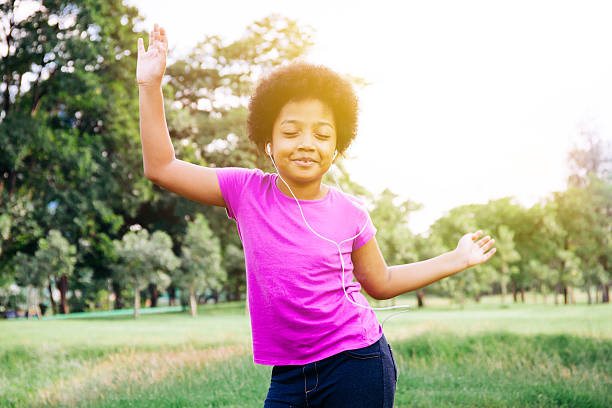 ragazzino che balla e ascolta musica nel parco verde - music listening child smiling foto e immagini stock