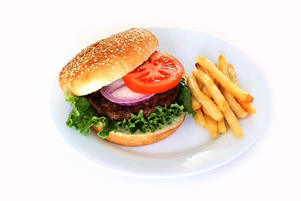 Photograph of a hamburger and fries set against a white background.  The burger is made with a beef patty, lettuce, tomato, red onion served on a sesame seed bun.