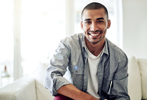 Portrait of a smiling young man sitting on the sofa in his living room