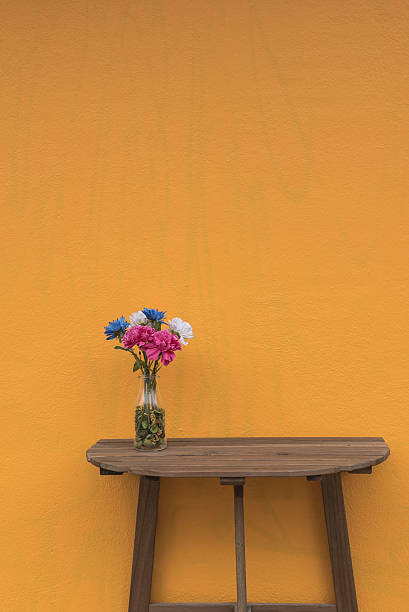 istock Flowers in a jar on a wooden table Yellow background . 629517114