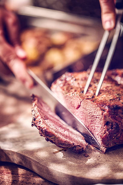 Cutting Roast Beef with Potatoes and Root Vegetables