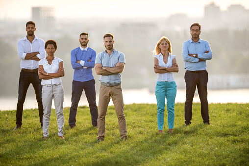 Confident business team standing in nature with their arms crossed and looking at the camera.