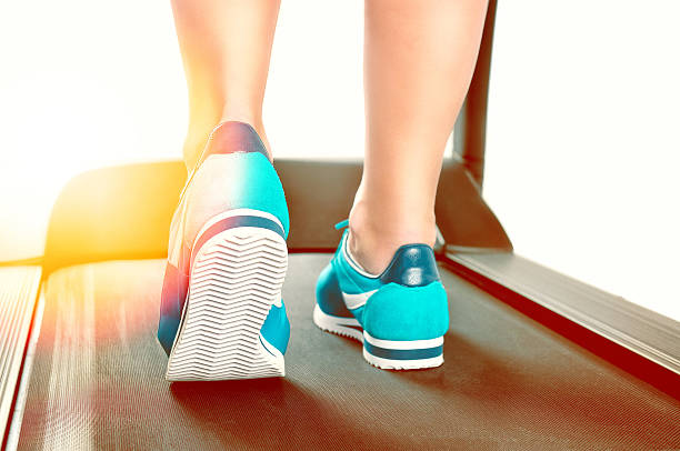 istock Female legs in turquoise sneakers on a treadmill 629531492