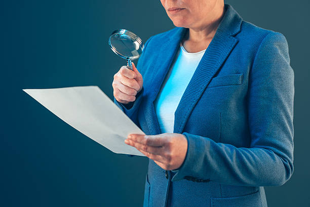 istock Female tax inspector looking at document with magnifying glass 629533452