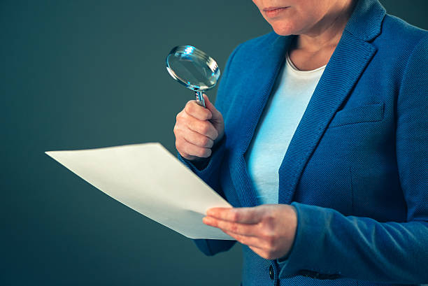 istock Female tax inspector looking at document with magnifying glass 629533652