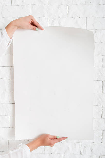 istock Blank poster in female hands against wall mockup 629553568