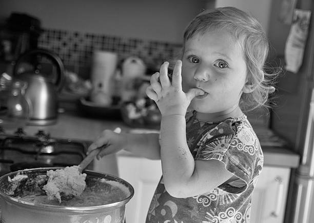 istock Cute girls eats away a dough, black and white 629555104