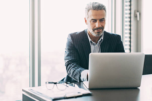 成熟したビジネスマンのオフィス - using laptop businessman laptop business ストックフォトと画像