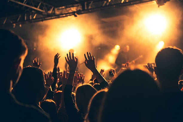 silhouettes of concert crowd in front of bright stage lights stock photo