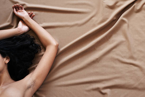 I think it's time for a new style Cropped shot of a woman with hair under her arms lying on a bed semi dress stock pictures, royalty-free photos & images