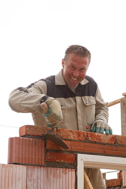 istock smiling bricklayer mason takes away the cement with trowel 629558342