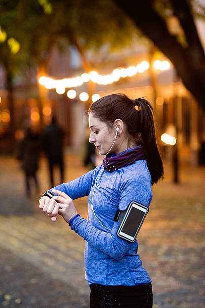 夜の町を走る青いスウェットシャツを着た若い女性 - arm band ストックフォトと画像