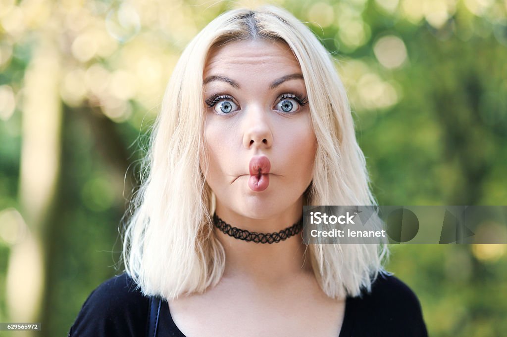 woman with funny face portrait of young blond beautiful woman making funny face looking at camera on the street Making A Face Stock Photo