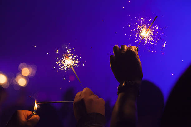 istock Sparklers burn in hands over dark blue 629566056