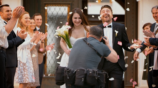 Photographer taking picture of newlywed bride and groom as they leave church.