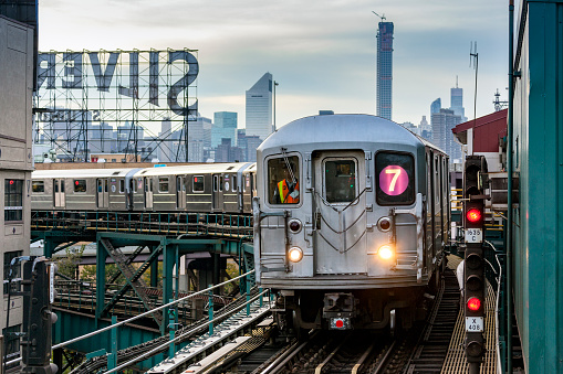 New York, United States - October 28, 2014: The driver of the rush hour MTA subway train on line 7 to Flushing Main Street from downtown Manhattan, watches intently as his train approaches Queensboro Plaza station.  The train has climbed up a steep elevated section of the railway to the station, past the famous Silvercup Studios sign.   The hazy, wintry New York skyline can be seen in the background. 