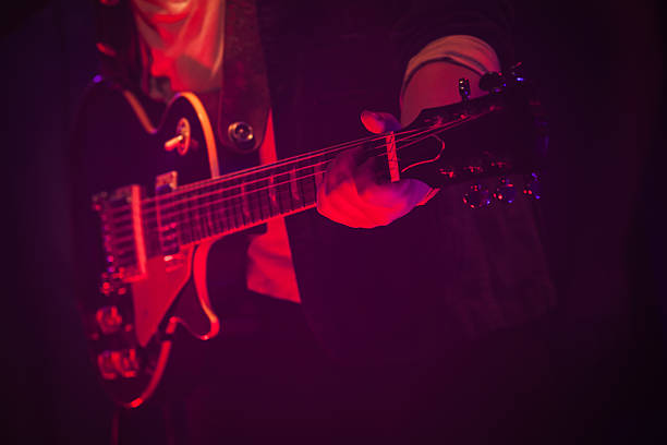 guitariste sur une scène avec une lumière rouge - light jazz photos et images de collection