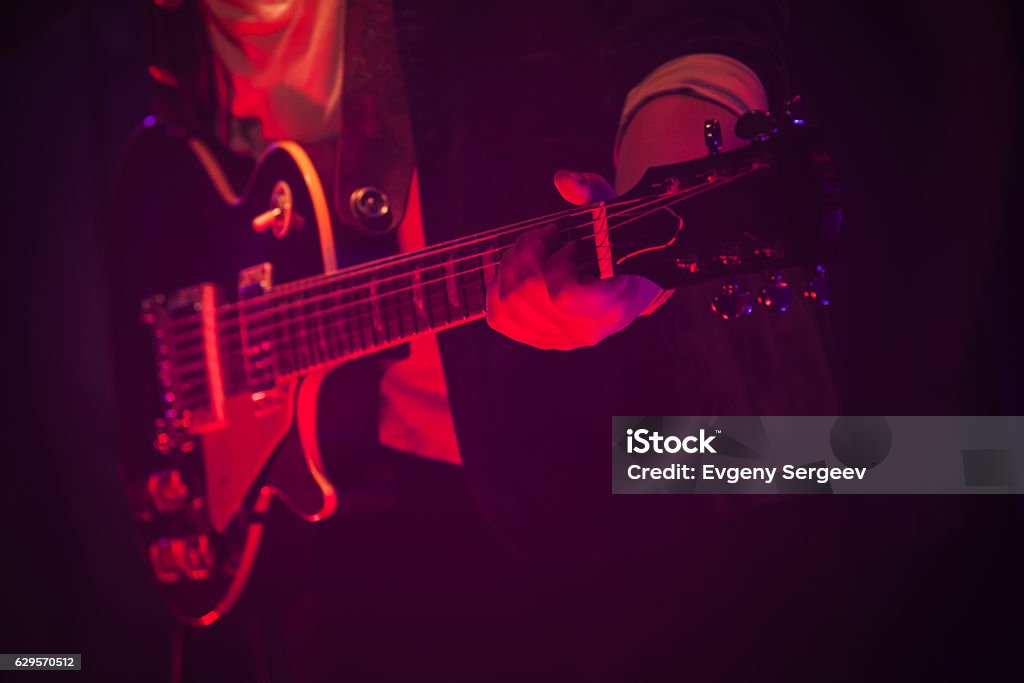 Guitar player on a stage with red light Electric guitar player on a stage with red scenic illumination, soft selective focus Guitar Stock Photo