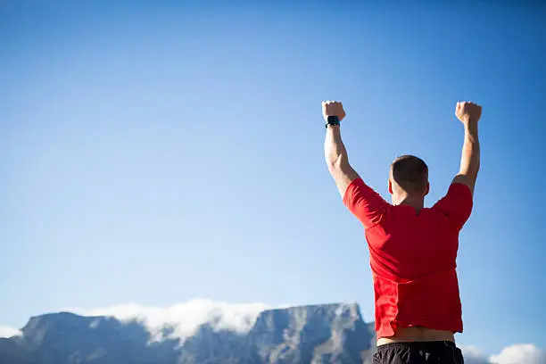 Photo of Man triumphantly nears the top of a mountain