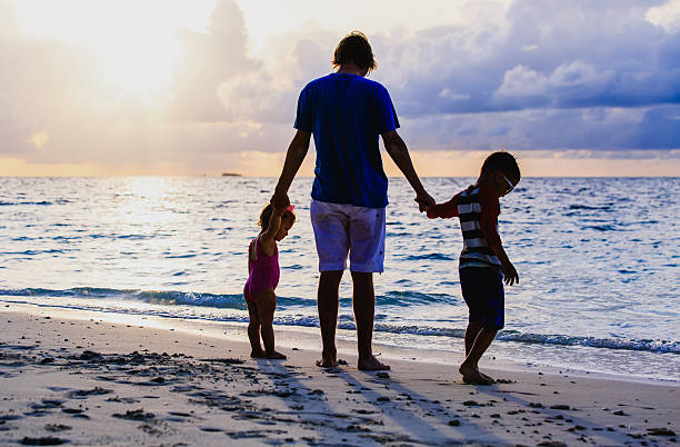 istock father and two kids walking at sunset 629579290
