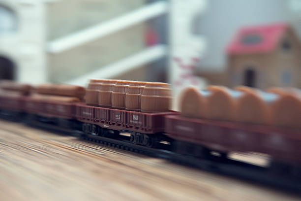 Close-up of miniature speeding freight train with boxcars: wood, barrels, spools; motion blur.