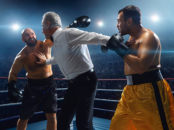 Boxing: Angry boxers A picture of a boxers who are going to continue the fight but referee separates them with his hands.  Sportsmen are on boxing ring with bleachers full of people boxing referee stock pictures, royalty-free photos & images