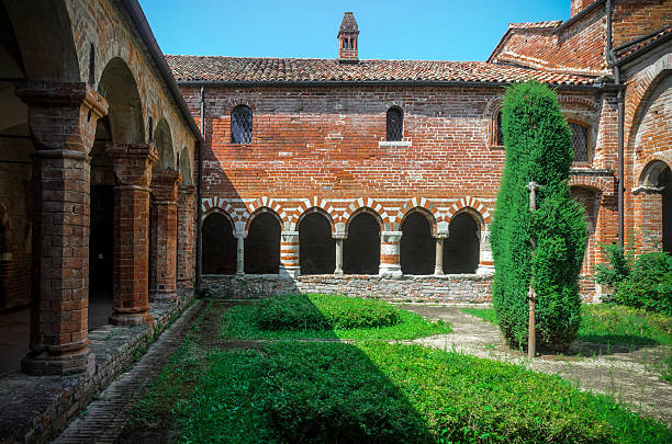 Albugnano (Italy) - July 24, 2016: Cloister of the abbey of Santa Maria di Vezzolano, in Albugnano (Italy), on july 24, 2016, with arcades, grass and a tree. The abbey is an example of romanesque architecture in Piedmont