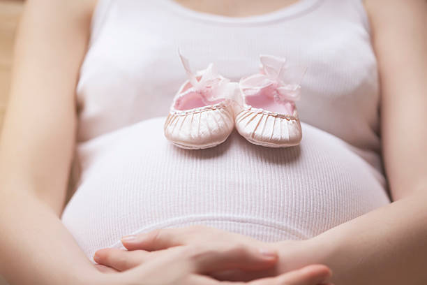 Pregnant woman and baby shoes stock photo