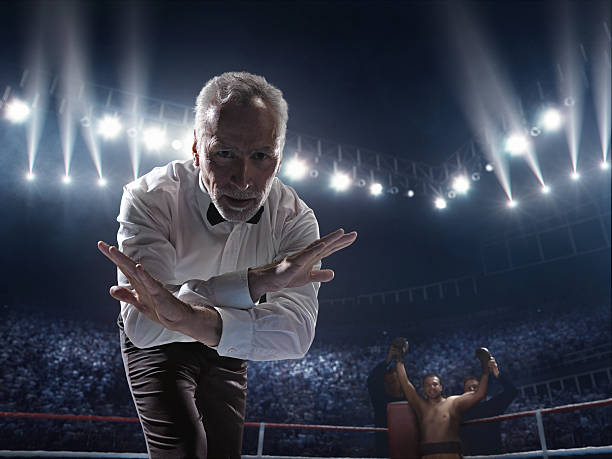 Boxing: Winner boxer A picture of a boxer who made knock out to the opposite one. Referee counts. Sportsmen are on boxing ring with bleachers full of people knockout stock pictures, royalty-free photos & images