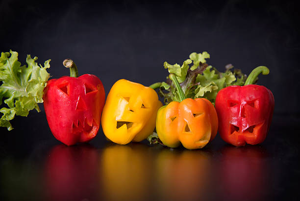 yellow sweet bell peppers with cutout faces stock photo