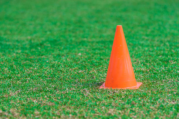 istock Orange cone standing on a green grass soccer field. 629586190