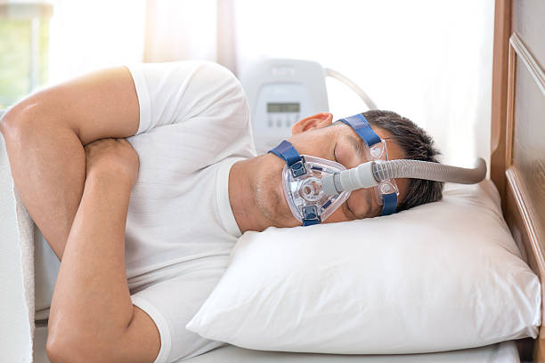 Man sleeping in bed wearing CPAP mask ,sleep apnea therapy Happy and healthy senior man sleeping deeply on his left side without snoring sleep apnea photos stock pictures, royalty-free photos & images
