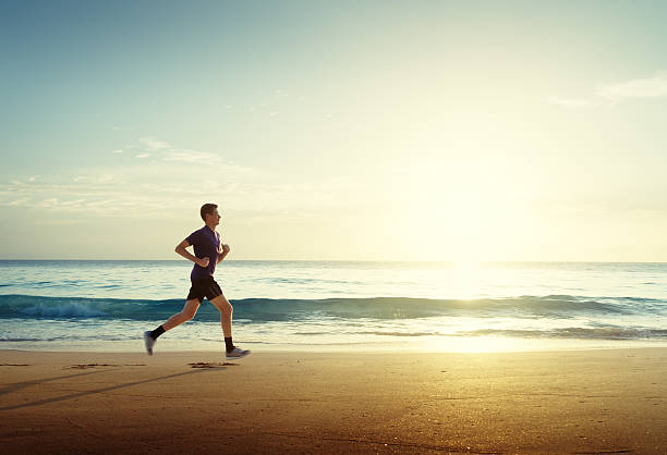 mann läuft bei sonnenuntergang am tropischen strand - men jogging running sports training stock-fotos und bilder