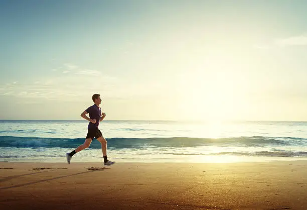 Photo of Man running on tropical beach at sunset