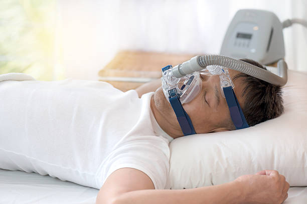 terapia de apnea del sueño, hombre durmiendo en la cama con máscara de cpap. - apnea del sueño fotografías e imágenes de stock