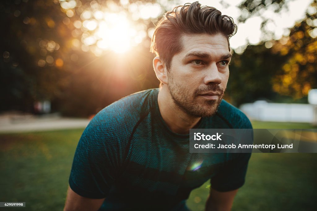 Healthy young man standing outdoors in park Close up portrait of healthy young man standing outdoors in park and looking away. Confident young man ready of workout. Men Stock Photo