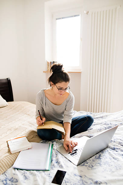 istock Beautiful young woman sitting on bed, working. Home office. 629593354