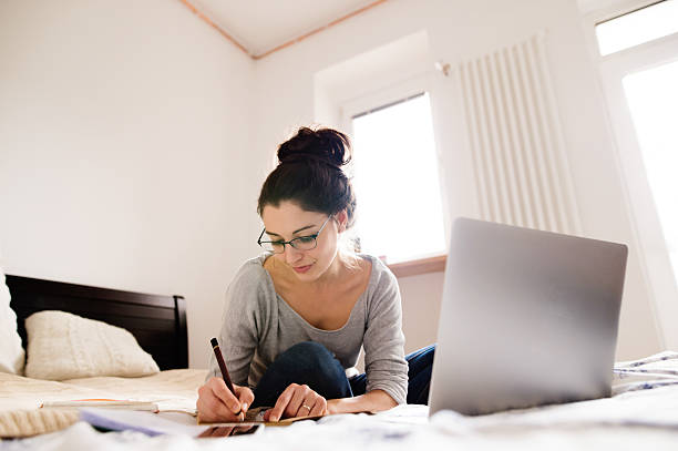 istock Beautiful young woman sitting on bed, working. Home office. 629593574