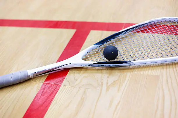 Photo of squash racket and ball on the court