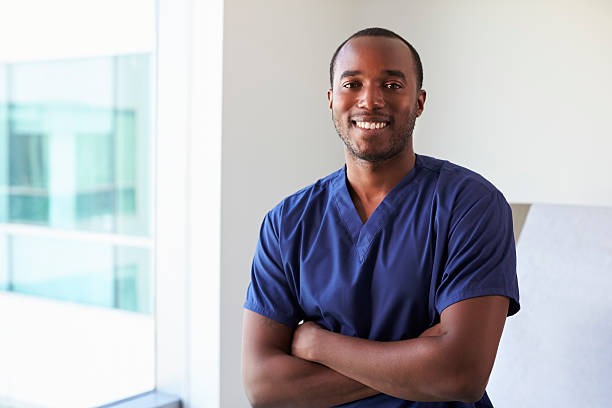 portrait of male nurse wearing scrubs in exam room - male nurse black nurse doctor imagens e fotografias de stock