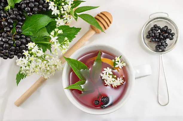 Cup of fresh elderberry tea with berries and honey