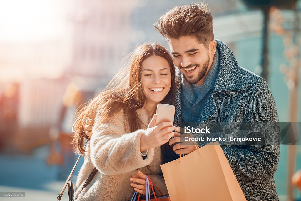 Couple in shopping Happy beautiful couple using smart phone and shopping together. Couple - Relationship Stock Photo