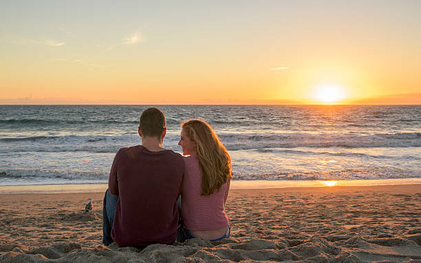 istock Young couple sitting on sandy beach at sunset 629604880