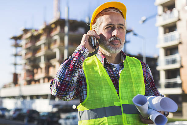 istock Adult male engineer holding blueprints while talking on his phone 629605216