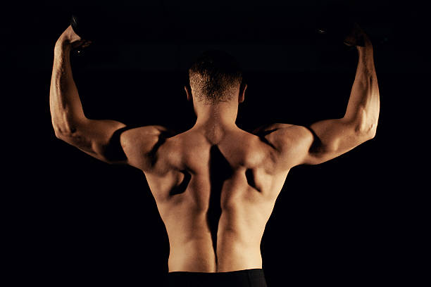 istock Muscular man with a dumbbell dark background 629606226